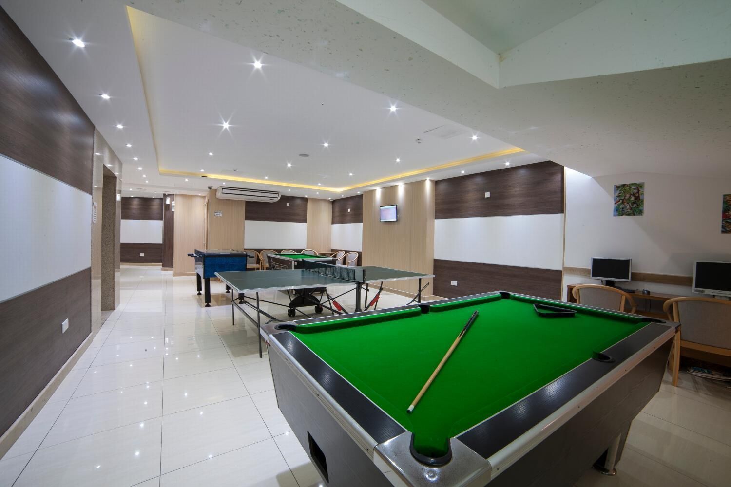 Een biljartzaal met meerdere tafels, een pooltafel en een televisiescherm.