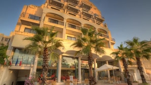A multi-story hotel with balconies, palm trees, and outdoor seating. - Bella Vista (Blue Ridge)