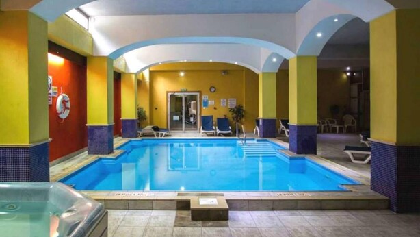 A swimming pool area with a tiled floor, a glass enclosure, and a few lounge chairs. - Bella Vista (Blue Ridge)