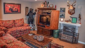 A living room with a sofa, a television, a fireplace, and a mounted deer head. - Tranquilidad (Blue Ridge)