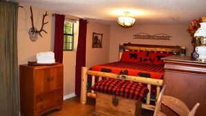 A cozy room with a wooden bed, a dresser, and a deer head mounted on the wall. - Tranquilidad (Blue Ridge)