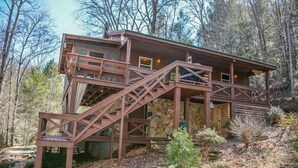 A cabin with a wooden exterior, a staircase, and a deck.