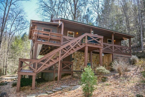 A cabin with a wooden exterior, a staircase, and a deck.