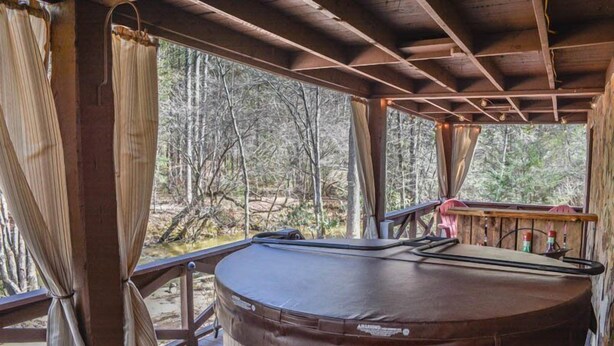 A hot tub on a wooden deck with a view of a forest.