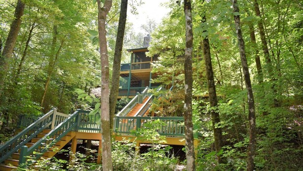 A multi-level wooden cabin with a staircase surrounded by dense forest. - Lucilles Creekside Hideaway (Blue Ridge)