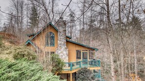 A log cabin with a stone chimney, a balcony, and surrounded by trees. - Lucilles Creekside Hideaway (Blue Ridge)