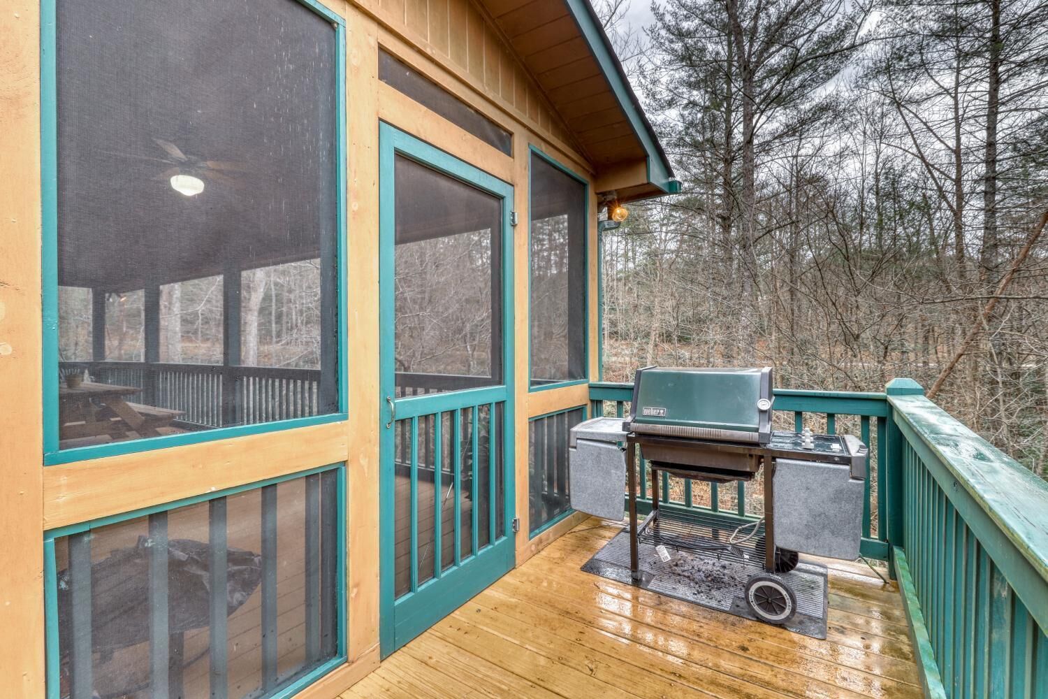 A wooden deck with a grill and a covered seating area.