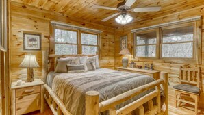 A wooden cabin bedroom with a bed, bedside tables, a chair, and a ceiling fan. - Lucilles Creekside Hideaway (Blue Ridge)