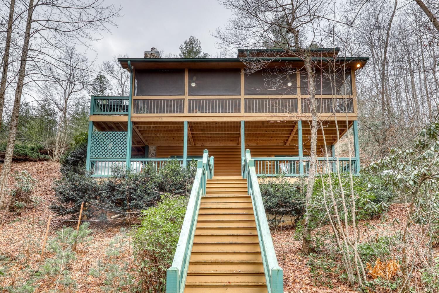 A wooden cabin with a balcony and a staircase leading to the entrance.