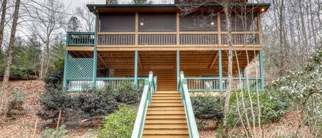 A wooden cabin with a balcony and a staircase leading to the entrance.