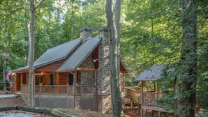 A rustic cabin with a stone chimney, wooden deck, and a covered porch. - Harleys River Retreat (Ellijay)