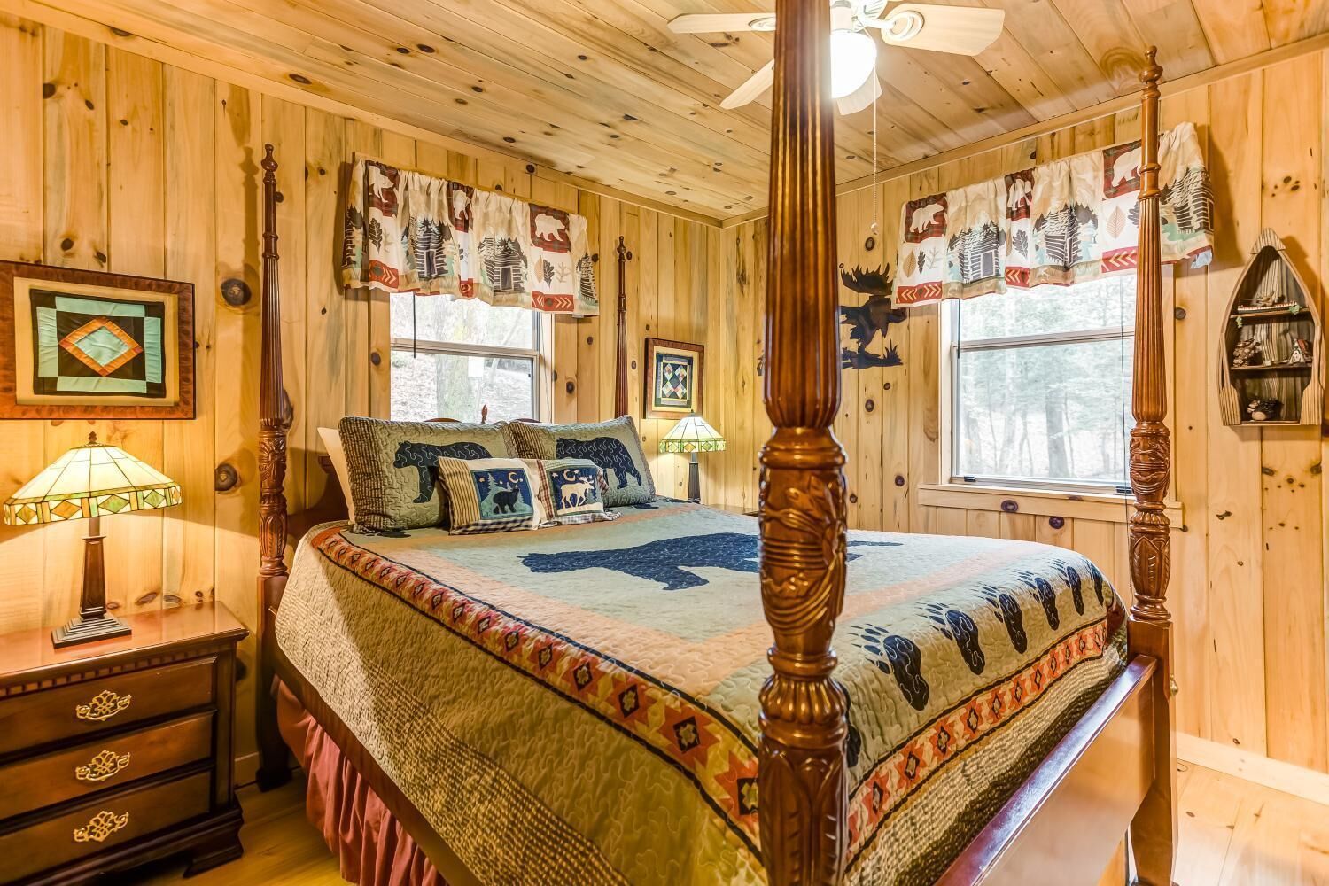 Un dormitorio con paneles de madera, una cama con dosel, almohadillas decorativas y una colcha con estampados de animales.