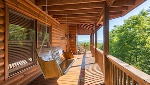 A wooden cabin with a porch, a swing seat, and a view of the forest. - Panoramic Paradise (Morganton)