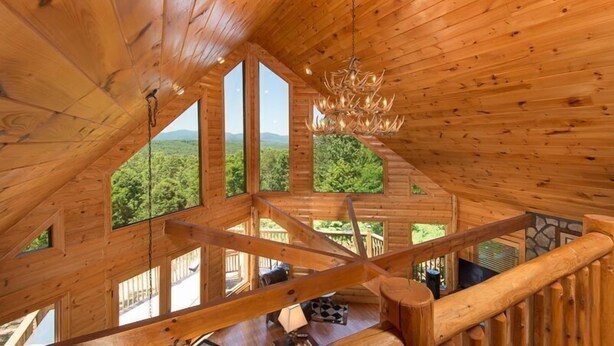 A wooden cabin with a sloped roof, large windows, and a chandelier. - Panoramic Paradise (Morganton)
