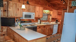 Una cucina in stile baita di legno, con forno a microonde, piano cottura, lavello e frigorifero.