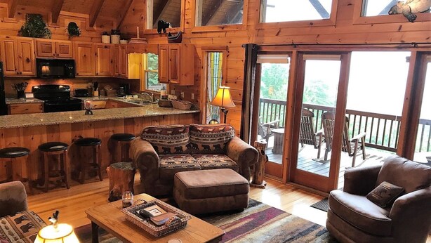 A cozy cabin interior with a wooden interior, a kitchen area, and a balcony with outdoor seating. - Light`s Mountain Lake Overlook (Blue Ridge)