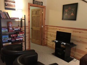A room with a wooden door, a television on a stand, and a shelf with board games. - Light`s Mountain Lake Overlook (Blue Ridge)