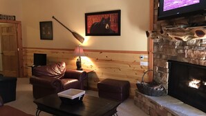 A cozy living room with a fireplace, leather furniture, and a television displaying a medical image. - Light`s Mountain Lake Overlook (Blue Ridge)