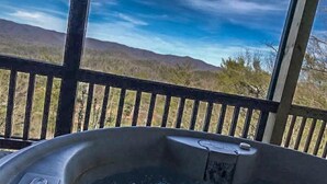A hot tub with a view of a mountainous landscape through a wooden railing. - Three Bears Bluff (Cherry Log)