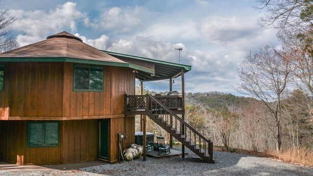 Eine Holzhütte mit einer Veranda und einer Treppe, die zu einer Terrasse führt.