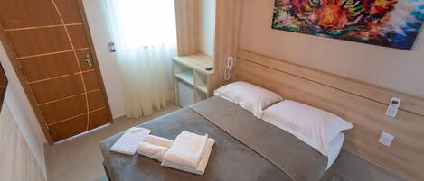 A neatly made bed with white linens, a wooden headboard, and a painting of a tiger on the wall.