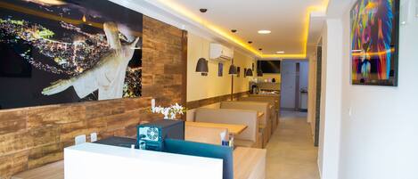 A modern hotel lobby with a reception desk, seating areas, and artwork on the walls.