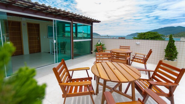A patio with wooden furniture and a glass door leading to a room. - Pousada Nascer do Sol (Arraial do Cabo)