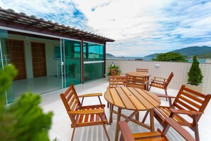 A patio with wooden furniture and a glass door leading to a room. - Pousada Nascer do Sol (Arraial do Cabo)