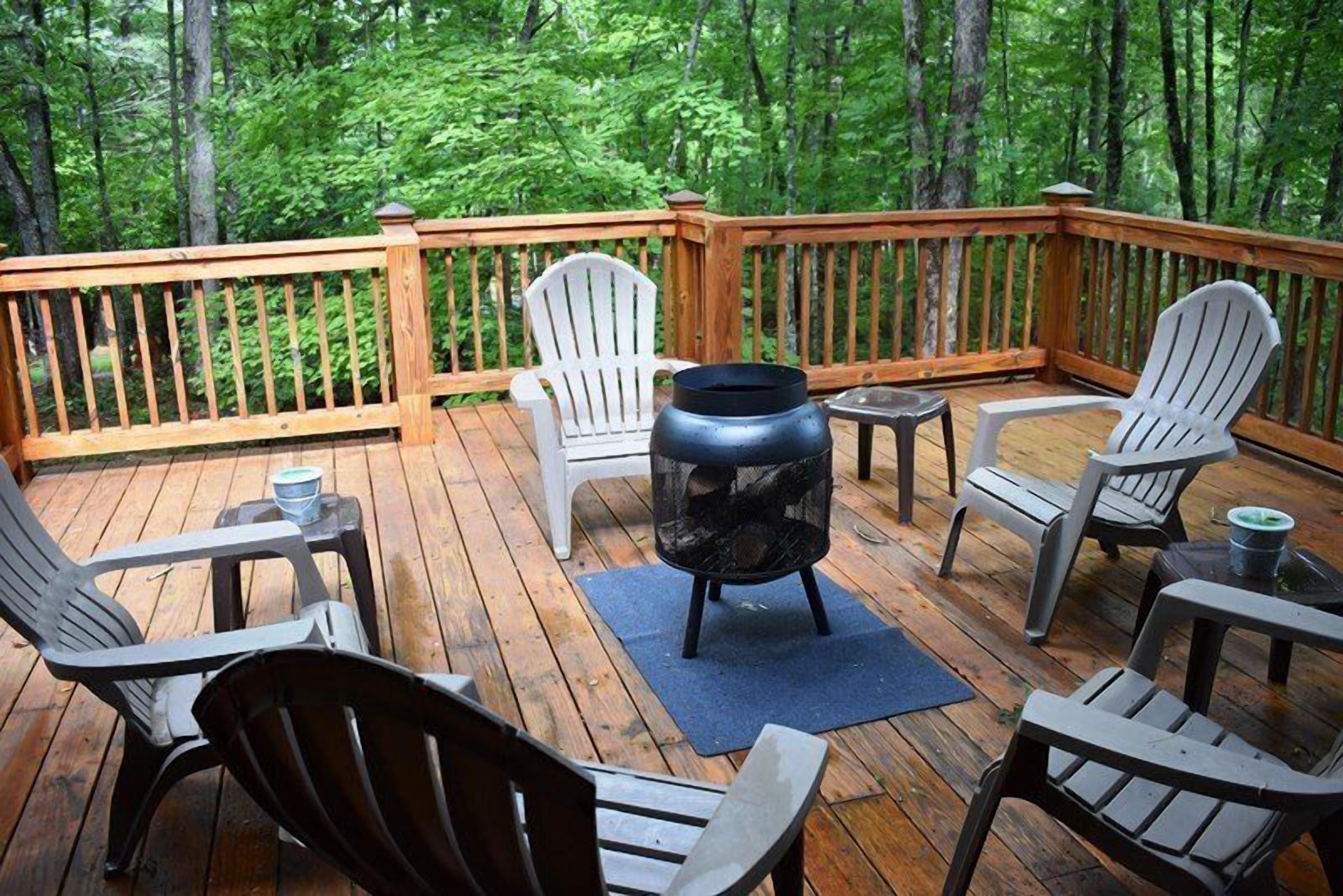 A wooden deck with Adirondack chairs and a fire pit.