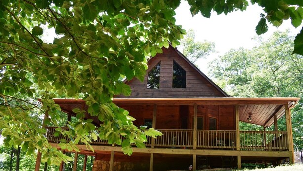 A wooden cabin with a porch and large windows, surrounded by trees. - Misty Mountain Hideaway (Morganton)
