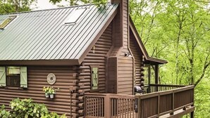 A log cabin with a metal roof, a wooden deck, and a small porch. - Acorn Bungalow (Blue Ridge)