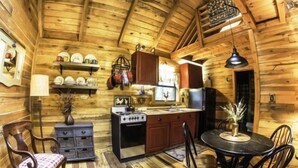 A cozy wooden cabin interior with a kitchen area, wooden walls, and a dining table with chairs. - Acorn Bungalow (Blue Ridge)