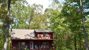 A cabin with a porch, surrounded by trees. - Firefly (Mineral Bluff)