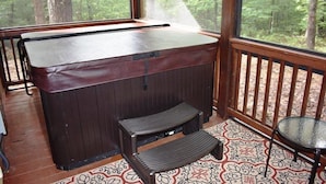 Une terrasse en bois avec un jacuzzi, une petite table et un banc.