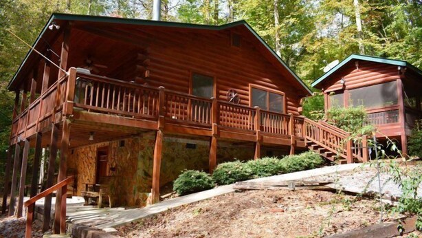 A rustic cabin with a wooden deck, a staircase leading to the entrance, and a small porch area. - A Cardinals Nest (Cherry Log)