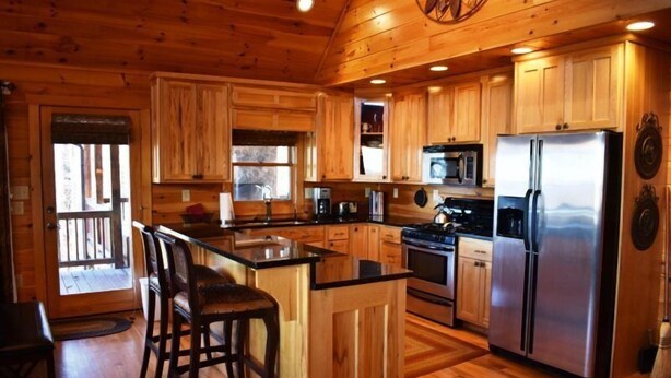 A wooden cabin-style kitchen with a central island, built-in appliances, and a large refrigerator. - Longview (Blue Ridge)