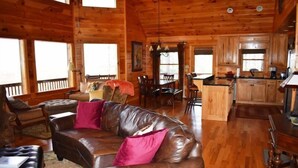 A wooden cabin interior with a leather sofa, dining area, and kitchen. - Longview (Blue Ridge)
