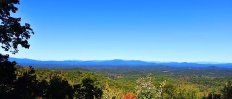 Eine gebirgige Landschaft mit dichtem Wald und strahlend blauem Himmel.
