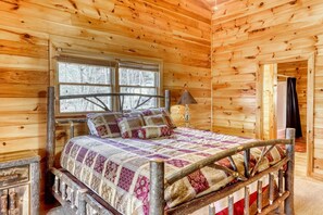 A wooden cabin bedroom with a bed, a window, and a lamp. - Under The Stars (Blue Ridge)