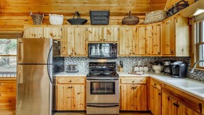 Una cucina con mobili in legno, elettrodomestici in acciaio inossidabile e una parete di fondo rivestita di piastrelle.