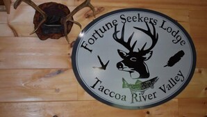 Una señal circular con la figura de un ciervo y el texto que dice 'Fortune Seekers Lodge Taccoa River Valley'.