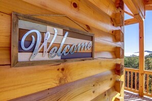 Una cabaña de madera con un letrero que dice 'Welcome' en la pared exterior.