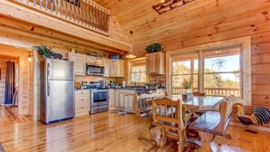 Una cocina amplia con pisos de madera, un comedor con una mesa y sillas de madera, y un ventanal que proporciona luz natural.