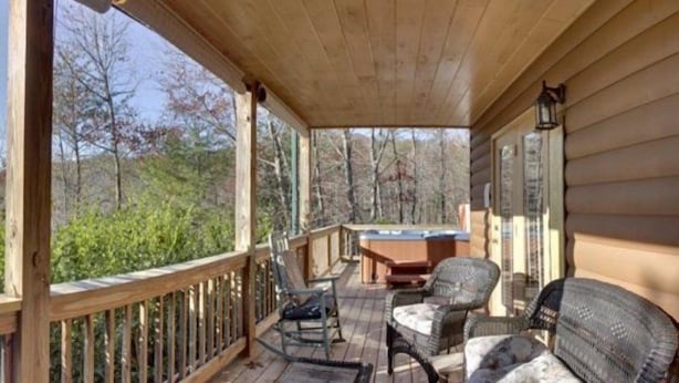 A wooden deck with wicker furniture and a hot tub. - Serenity (Blue Ridge)