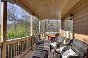 Une terrasse en bois avec des meubles en osier et un jacuzzi.
