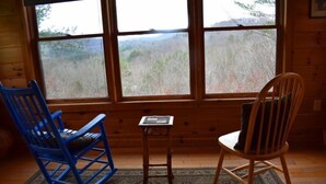 A room with wooden walls and large windows. There are two chairs, one blue and one brown, and a small table with a keyboard. - Serenity (Blue Ridge)