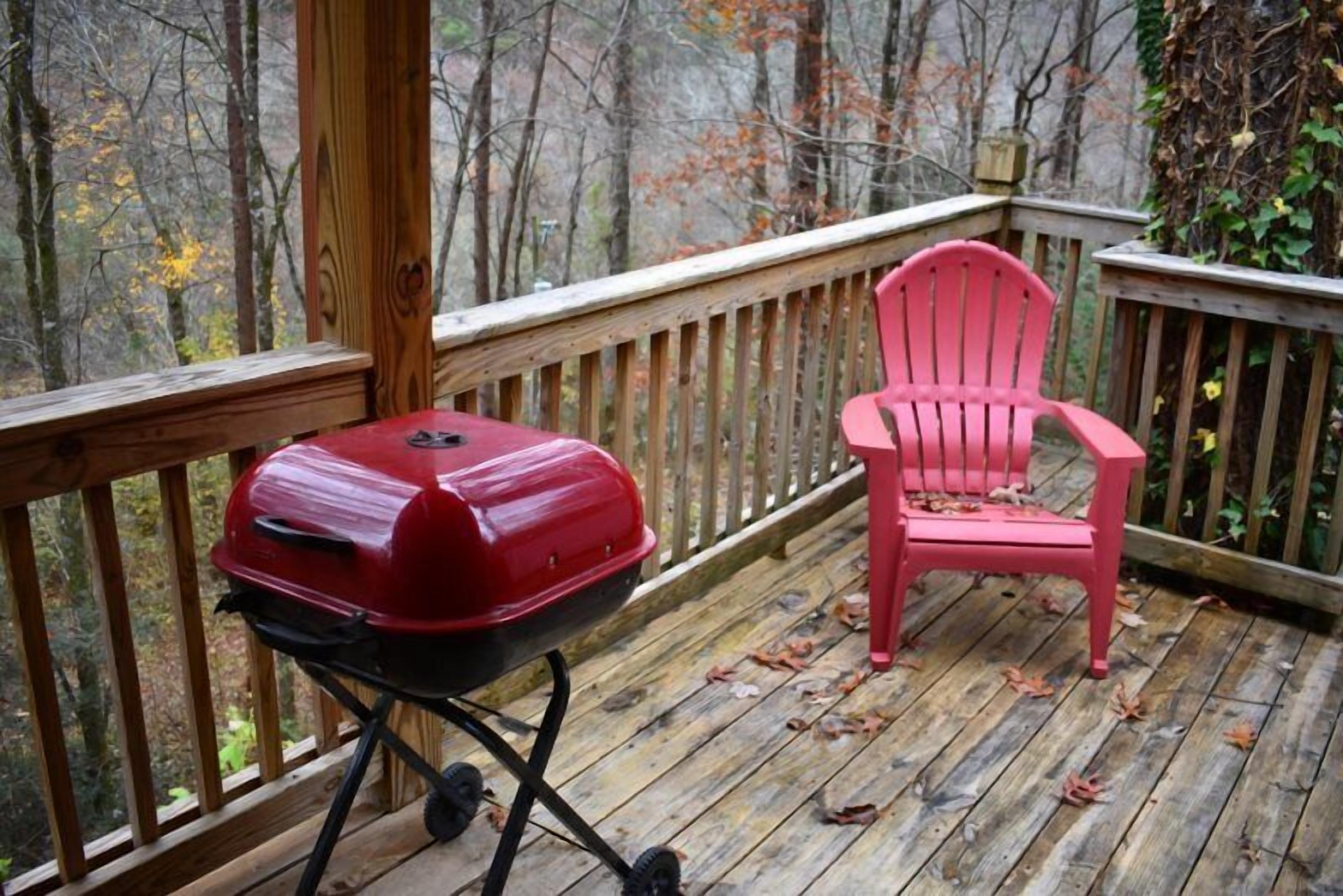A wooden deck with a red grill and a pink chair.