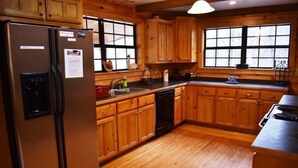 A kitchen with wooden cabinets, a refrigerator, a sink, and a dishwasher. - Misty Lake Lodge (Blue Ridge)