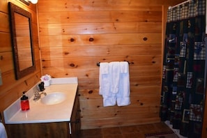 Un baño con paredes de madera, un lavamanos, un espejo y un perchero para toallas.