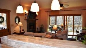 Un salon doté d’un îlot central en marbre, d’une cheminée et d’une grande fenêtre offrant une vue imprenable.